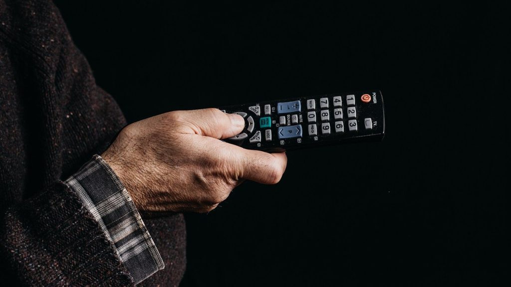Hand mit Fernbedienung vor dem Fernsehabend