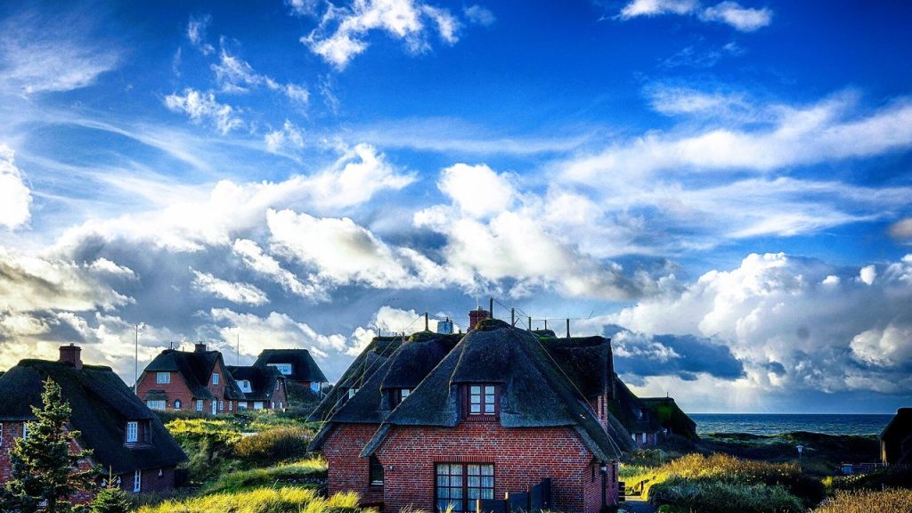 Reetgedeckte Friesenhäuser in Rantum auf Sylt unter wechselhaftem Himmel
